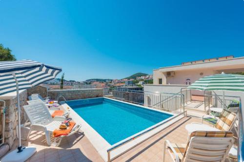 a swimming pool on a balcony with chairs and an umbrella at Villa Borna Apartments in Dubrovnik