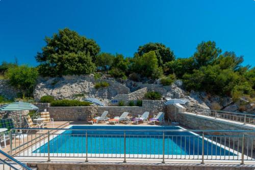 a swimming pool with chairs and umbrellas on a hill at Villa Borna Apartments with Free Parking in Dubrovnik
