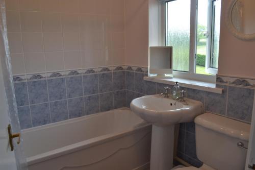 a bathroom with a sink and a toilet and a tub and a sink at Palm Tree Cottage in Stokeinteignhead