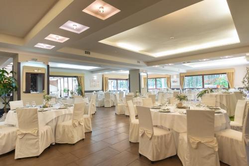 un salón de banquetes con mesas y sillas blancas en Parco dei Pini - Sila Wellness Hotel en Taverna