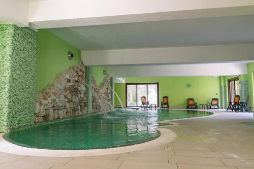 a swimming pool with a fountain in a room with green walls at Parco dei Pini - Sila Wellness Hotel in Taverna