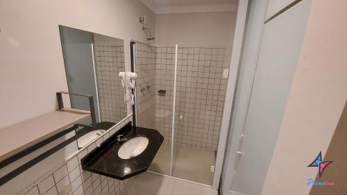 a bathroom with a sink and a mirror and a toilet at Hotel PrimeInn in Campinas