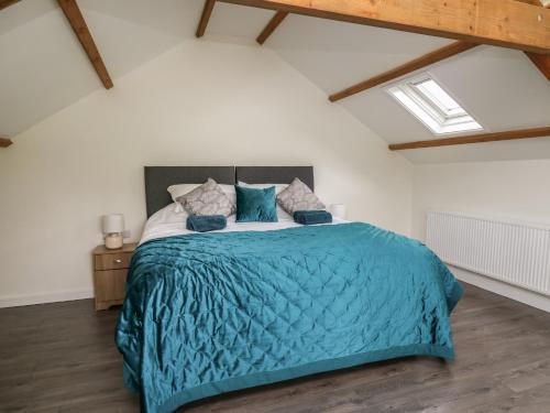 a bedroom with a large bed with a blue blanket at Cwrt y Wennol in Swansea