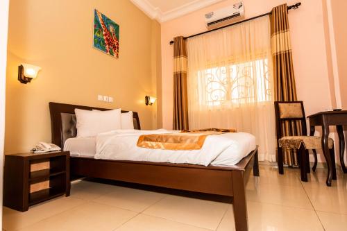 a bedroom with a bed and a table and a window at ISIS Hôtel in Yaoundé