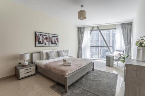 Dormitorio blanco con cama y ventana grande en HiGuests - Luxury Apartment in the Iconic Park Towers, en Dubái