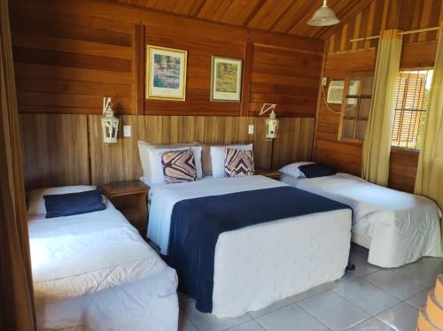 two beds in a room with wooden walls at Pousada Mon Desir in Penedo