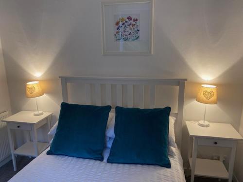 a bedroom with a bed with blue pillows and two lamps at Self-contained luxurious feel apartment in Dunfermline