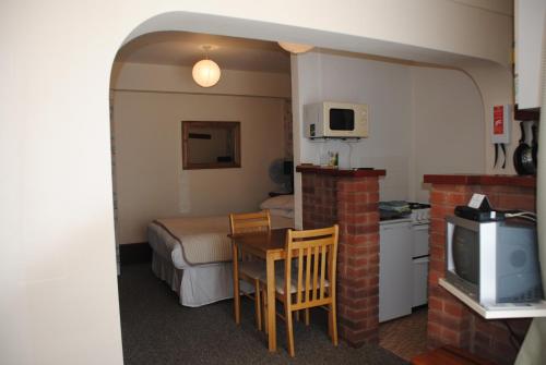 a small room with a bed and a table and a kitchen at Ottery Tor in Stokeinteignhead