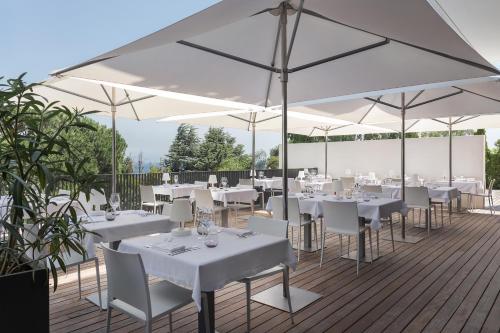 a restaurant with white tables and white umbrellas at Grand Hotel Du Golfe - Spa & Restaurant in Collioure