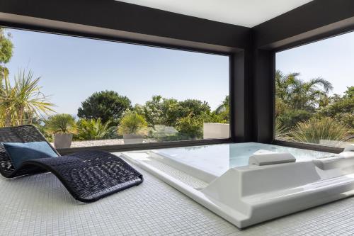 a glass table and chairs in a room with a large window at Grand Hotel Du Golfe - Spa & Restaurant in Collioure