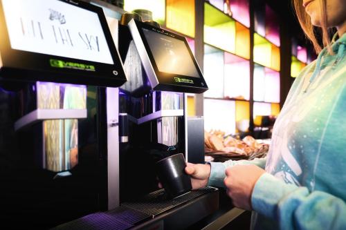 a person holding a cup in front of a machine at Hit the Sky in Sankt Christoph am Arlberg