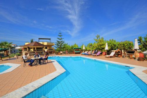 una piscina en un complejo con gente sentada en una mesa en Kreta Natur, en Hersonissos