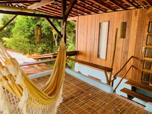 a hammock on the deck of a cabin at CASA AITI, ex-Casa da Cris e Paulo in Ilha de Boipeba