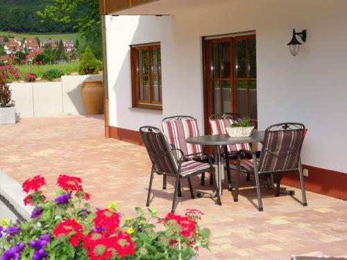 a patio with a table and chairs and flowers at Ferienwohnungen Braun in Seelbach