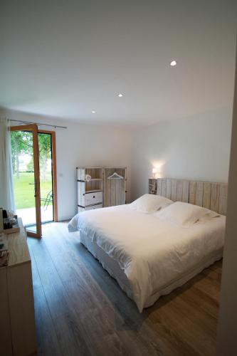 une chambre avec un grand lit blanc et une fenêtre dans l'établissement La Balade des Marais, à Saint-Molf