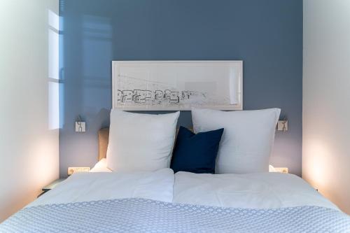 a bed with white sheets and blue pillows at Strandhaus Düne 19 - Freude in Neuhaus