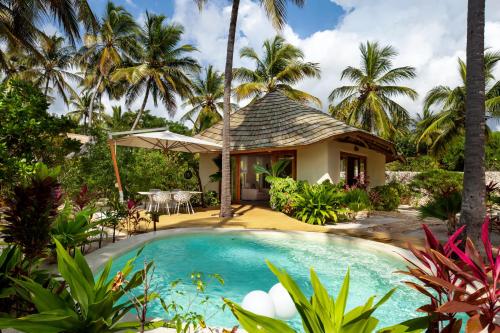 a villa with a swimming pool and palm trees at Zanzibar White Sand Luxury Villas & Spa - Relais & Chateaux in Paje