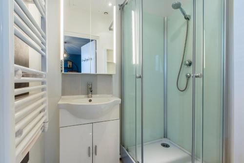 La salle de bains est pourvue d'un lavabo et d'une douche en verre. dans l'établissement Appartement style industriel, propre, WIFI Fibre, à Roncq