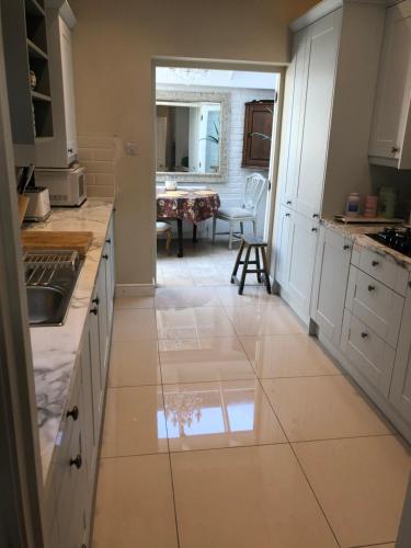 a kitchen with white cabinets and a tile floor at Victoria Villas in London