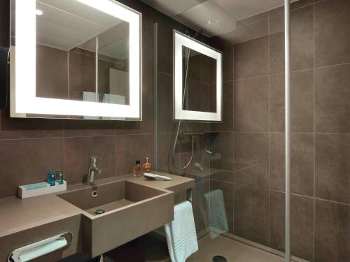 a bathroom with a sink and a shower at Novotel Roissy Saint Witz in Saint-Witz