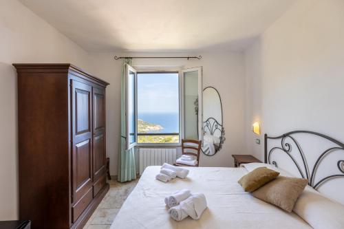a bedroom with a bed and a large window at Hotel Castello Monticello in Giglio Porto