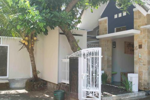Cipta Guesthouse في يوغياكارتا: بوابة بيضاء امام بيت فيه شجرة