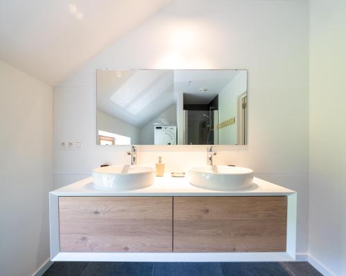 a bathroom with two sinks and a large mirror at Le Grenier du Moulin in Héron