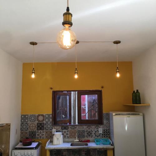 a kitchen with yellow walls and a window and lights at Vila Hibisco Itacaré in Itacaré