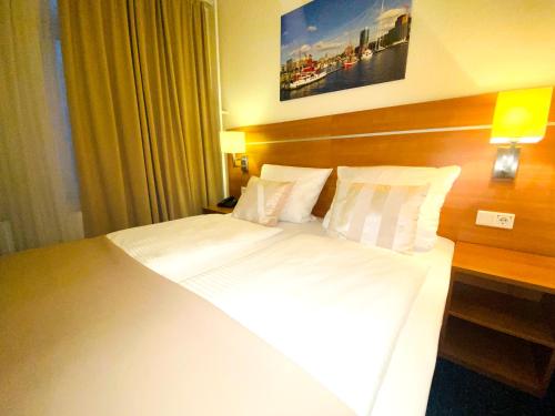 a bedroom with a large bed with white sheets and pillows at Hotel Hansehof in Hamburg