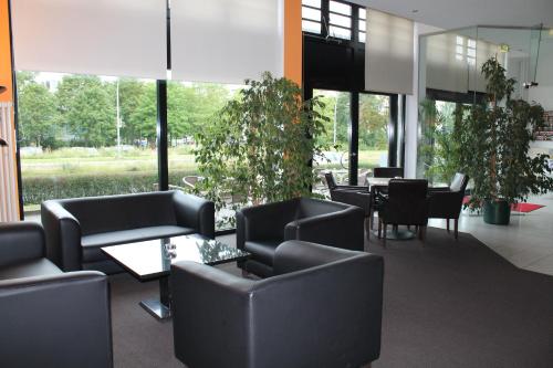 a lobby with black chairs and tables and windows at Hotel Sedes in Berlin
