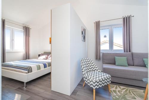 um quarto com uma cama, um sofá e uma cadeira em House of Dalmatia em Pakoštane