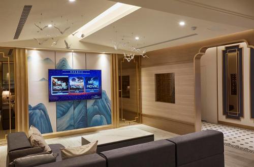 a living room with a couch and a tv on a wall at Motel Lin in Taichung