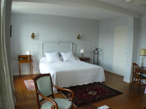 a bedroom with a white bed and two chairs at La Maison de Saumur in Saumur