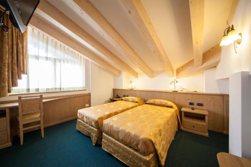 a bedroom with two beds and a window at Family Hotel Andes - Only for Family in Vigo di Fassa