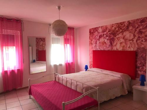 - une chambre avec un lit rouge et un miroir dans l'établissement Corallo - a 50m dall'Ospedale!, à Negrar