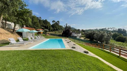 a swimming pool in the middle of a yard with chairs at Casa da Torre in Lapela