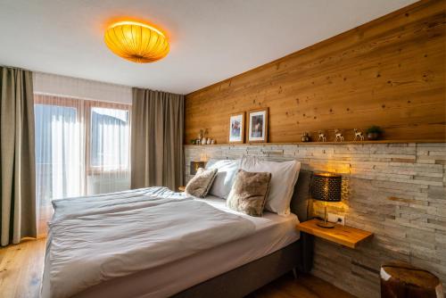 1 dormitorio con 1 cama grande y pared de madera en Ferienwohnung Marlies, en Bartholomäberg