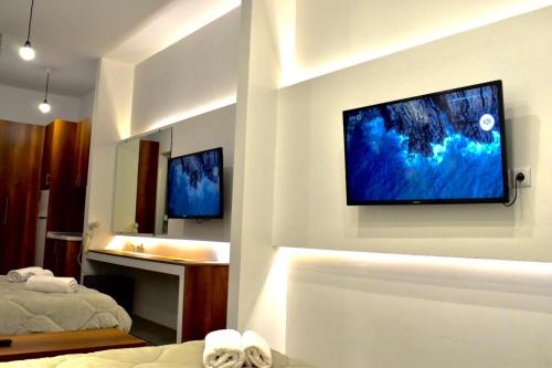 een woonkamer met een televisie aan de muur bij Sophia seaview suites & restaurant in Nea Vrasna