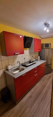 a kitchen with red cabinets and a sink at POKOJE GOŚCINNE JANINA ,Szklarska Poreba Dolna in Szklarska Poręba