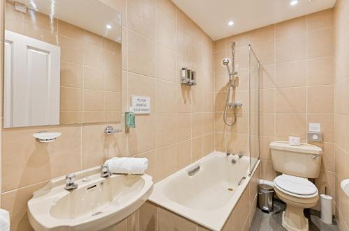 a bathroom with a tub and a toilet and a sink at Alma Accommodation - TV in Every Bedroom! in Swansea
