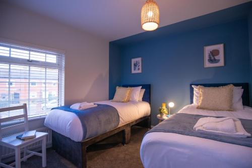 een slaapkamer met 2 bedden en een blauwe muur bij Saltbox Properties- LARGE!! 3 bed, 3 bath house, parking, fast wifi, town centre location! sleeps 6 in Ashby de la Zouch