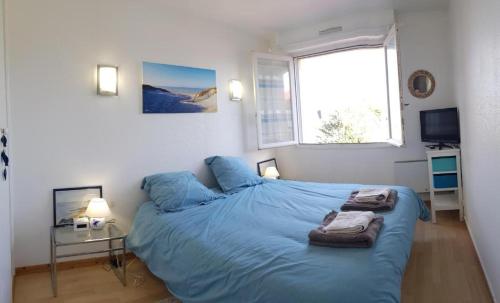 1 dormitorio con cama con sábanas azules y ventana en Grand appartement traversant 3 ch hyper-centre+Parking privé. en Le Touquet-Paris-Plage