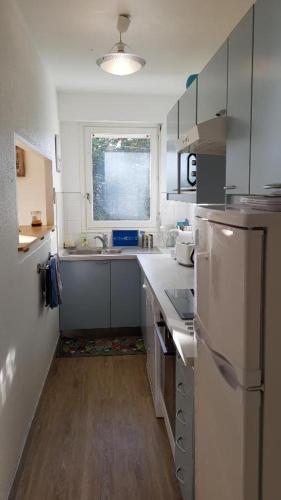 une petite cuisine avec un évier et un réfrigérateur dans l'établissement Grand appartement traversant 3 ch hyper-centre+Parking privé., à Le Touquet-Paris-Plage