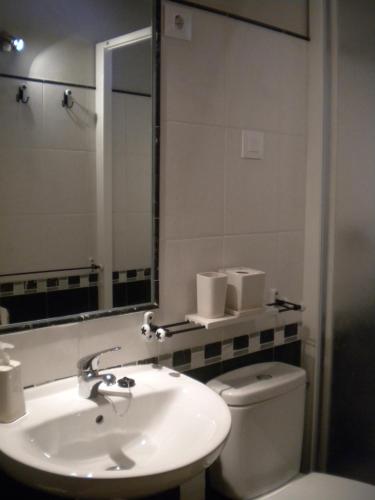 a bathroom with a sink and a toilet and a mirror at Hostal Rural Las Cuatro Calles in San Martín del Pimpollar