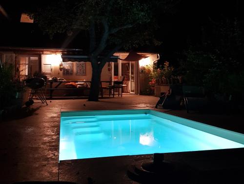 a blue swimming pool in a yard at night at Le Petit Studio in Cosswiller