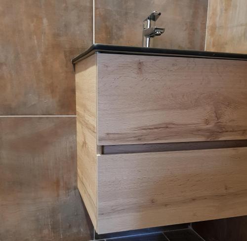 a wooden cabinet with a faucet in a bathroom at Le Petit Studio in Cosswiller
