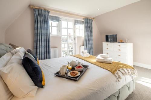 1 Sanctuary Court - Aldeburgh Coastal Cottages في قرية ثوربنيس: غرفة نوم مع صينية طعام على سرير