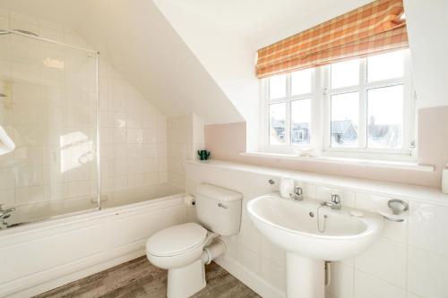 a white bathroom with a toilet and a sink at 1 Sanctuary Court - Aldeburgh Coastal Cottages in Thorpeness