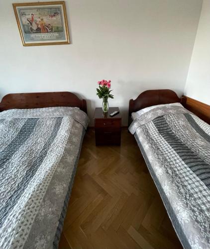 two beds in a room with a vase of flowers at Hotel Europa in Polanica-Zdrój