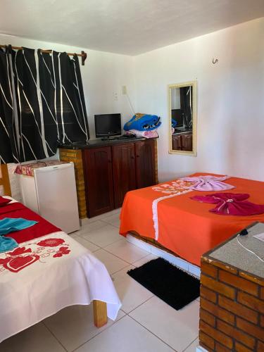 um quarto com duas camas e uma televisão em Pousada Casa da Lu em Aracati